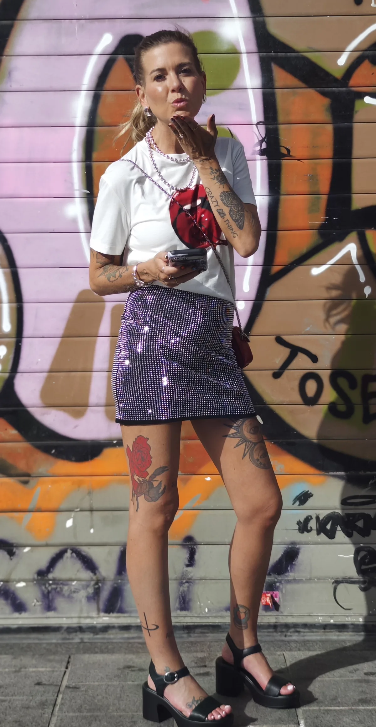 Cortnie blowing a kiss in front of a bright graffiti wall in Barcelona